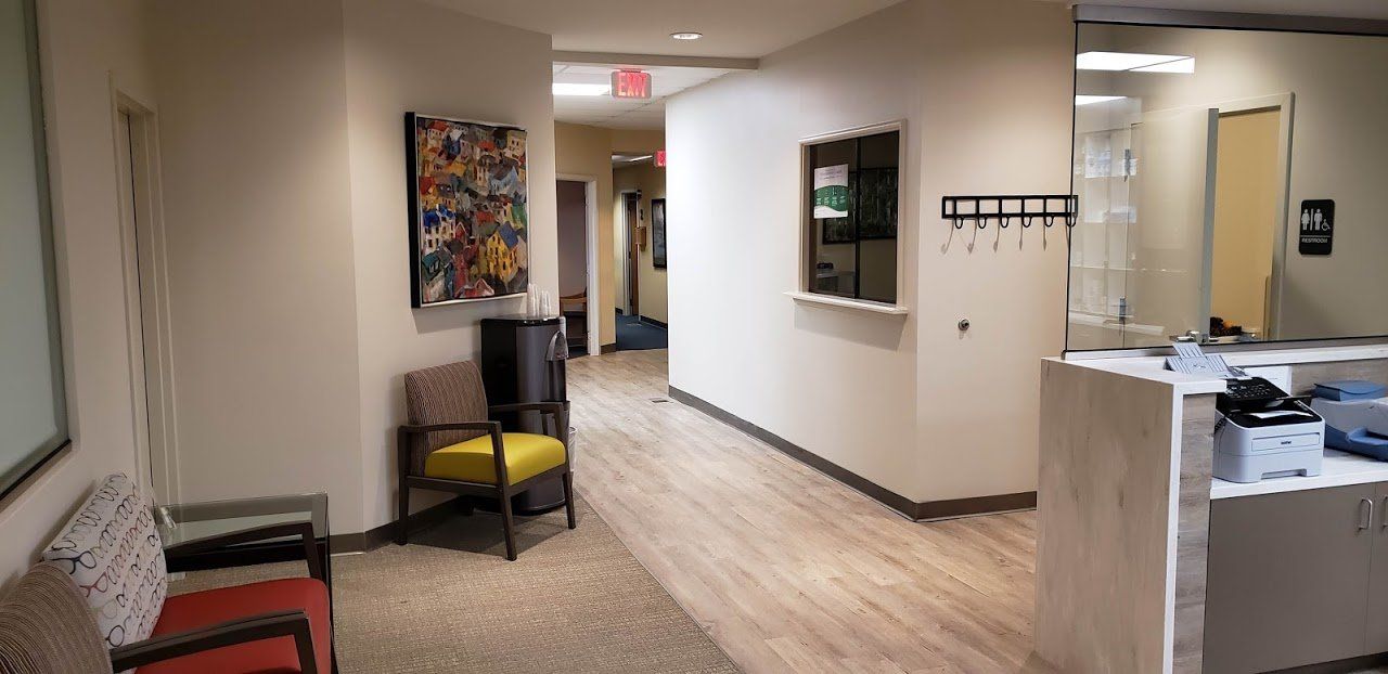 A long hallway with chairs and a counter in a dental office.