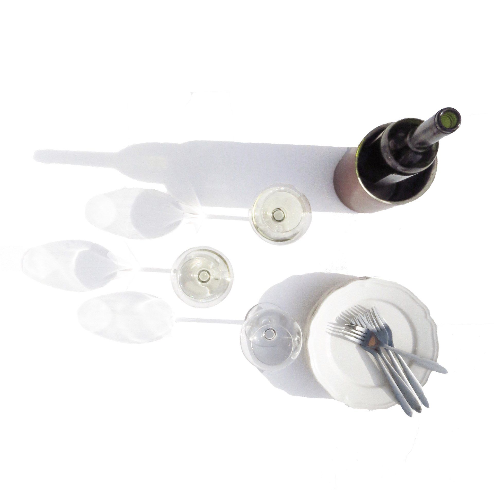 Chilled white wine, wine glasses, white plates and forks on a white background in the sun