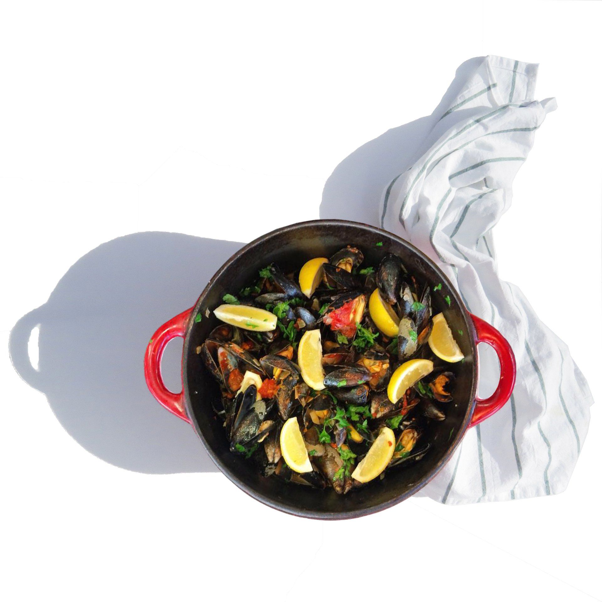 Top-down view of a red pot of seafood mussels stew with tomato sauce and with lemon wedges on a white cloth