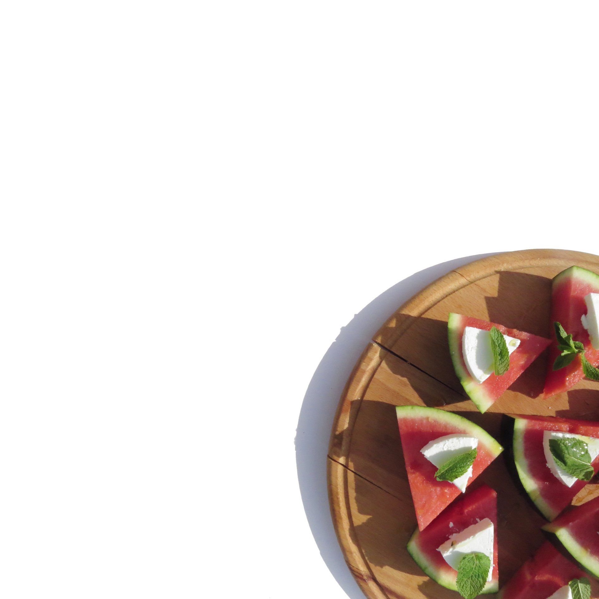 Plate with sliced watermelon with feta and mint on a wooden board