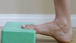 A person is standing on a green block with their foot on it.