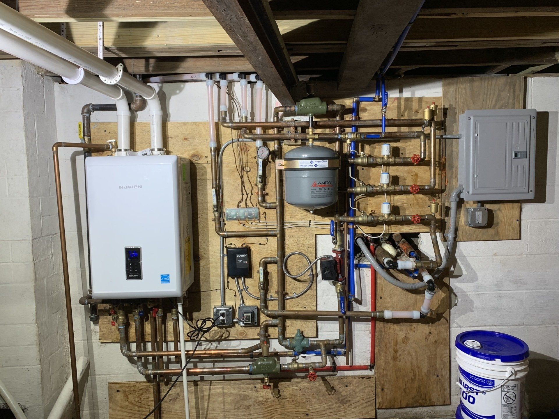 The image displays a high-efficiency Navien combi boiler system with associated plumbing, which provides both hot water and space heating.