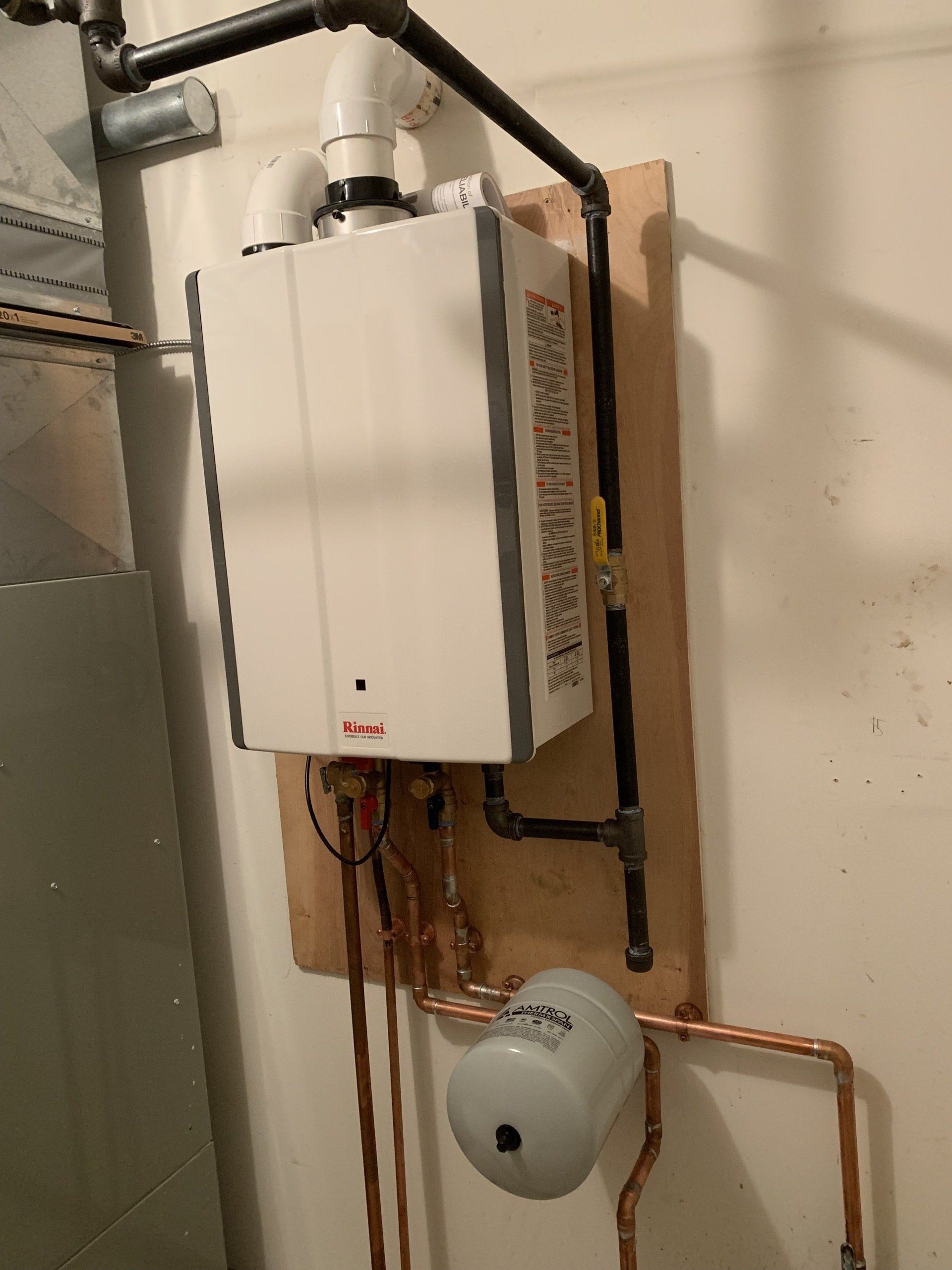 The image displays a Rinnai tankless water heater installation, which provides hot water on demand.