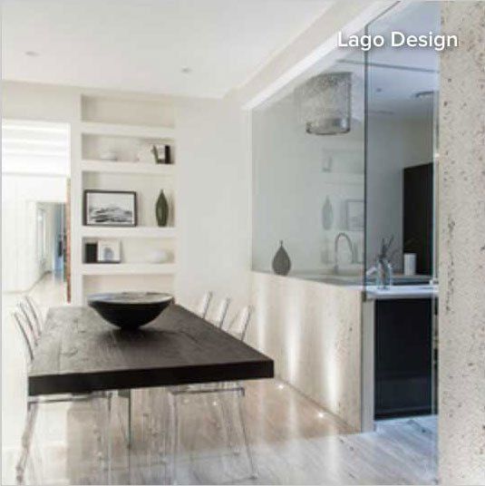 Glass wall to kitchen area beyond. Heavy table with light chairs
