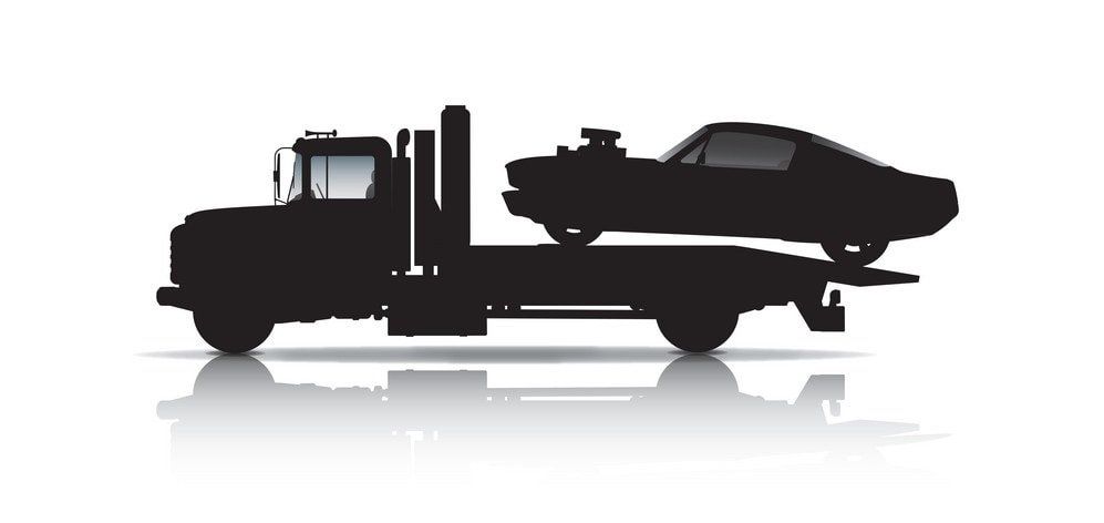 Silhouette of a tow truck carrying a car on a white background