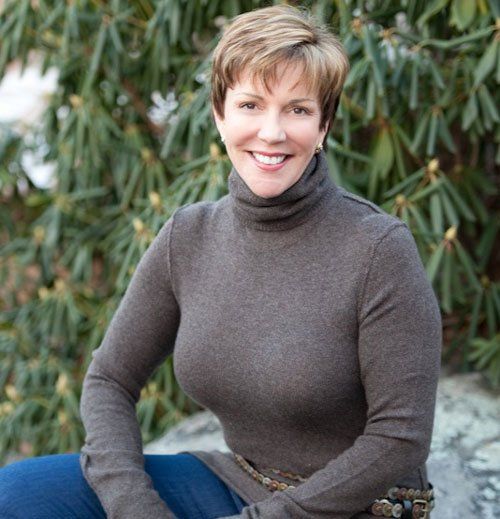 Judy wearing a brown turtleneck is smiling for the camera