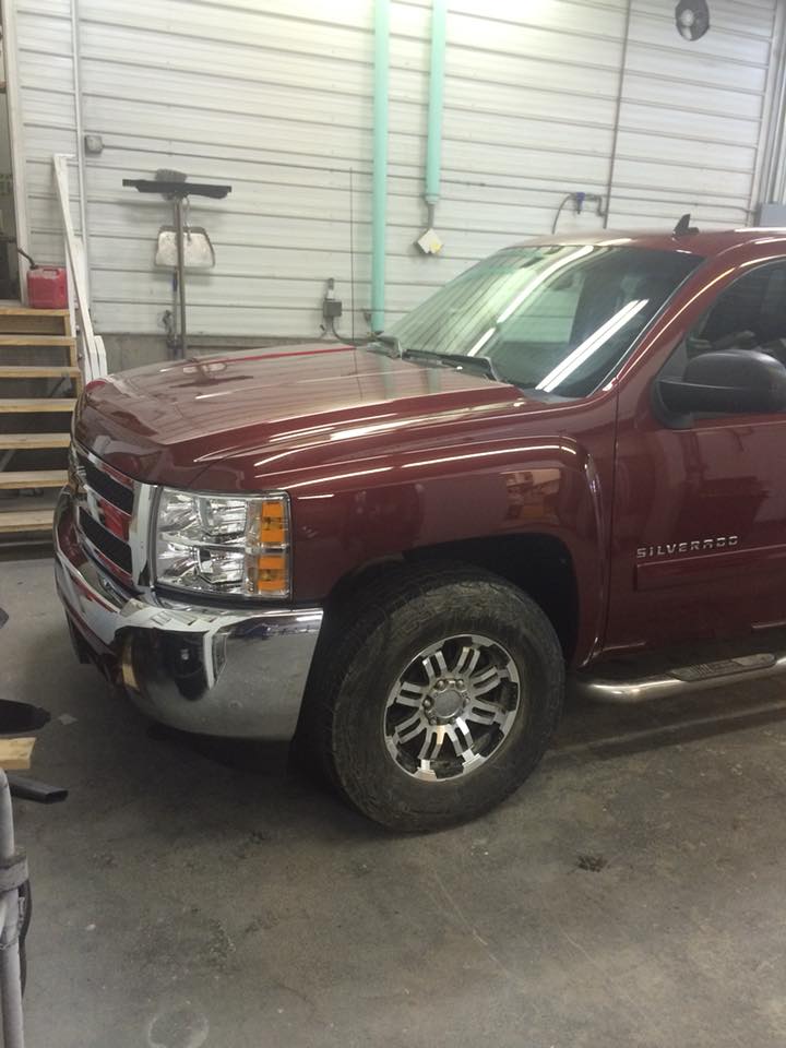 Maroon pickup truck parked in a garage, viewed from the front-left side.