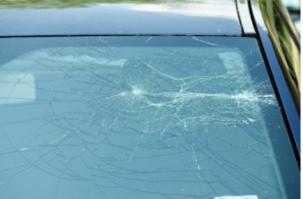Cracked car windshield with a spiderweb impact near the center