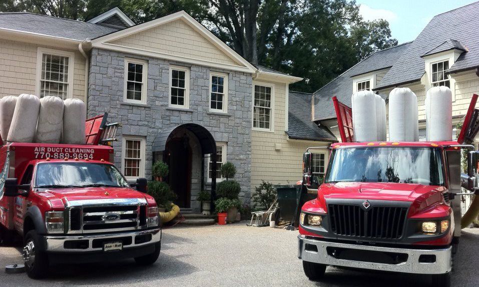 Two red trucks are parked in front of a large house