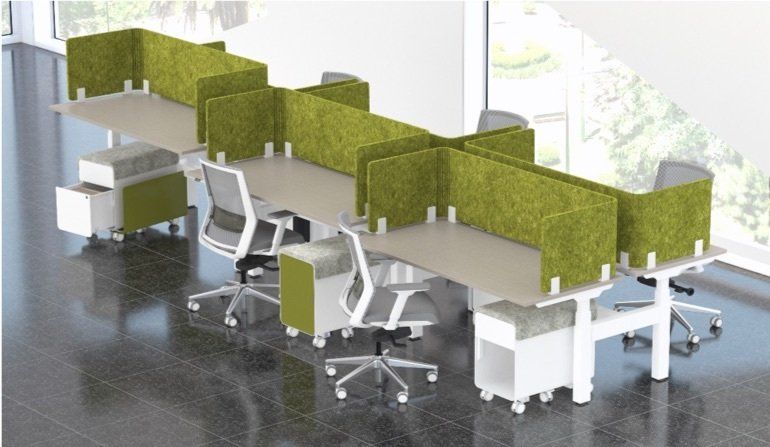 Office desks with green partitions and chairs, white and green storage units against a window.