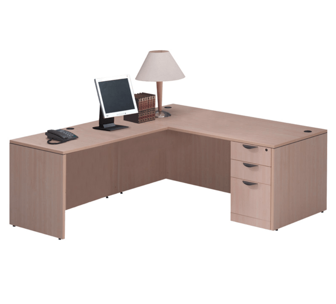 L-shaped beige office desk with a monitor, lamp, phone, and drawers.