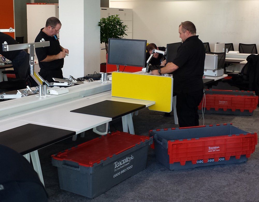 Two men are working in an office with a yellow desk divider