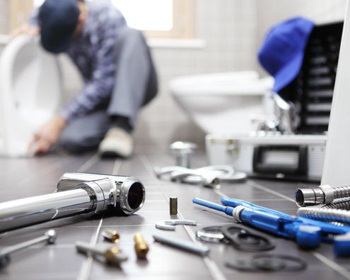 Plumber At Work In A Bathroom — Moline, IL — Erickson Plumbing & Heating A plumber working on plumbing repairs in Davenport, IA