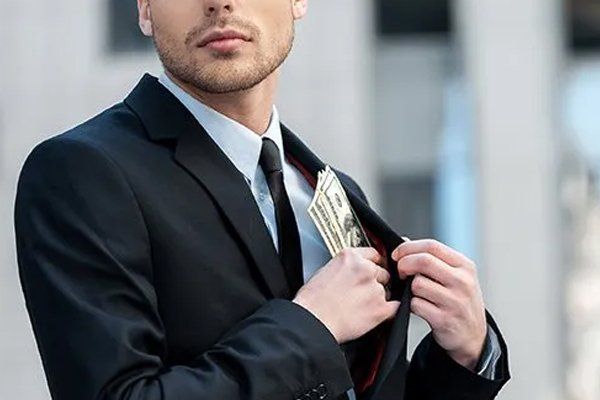 Businessman Putting Money Into His Pocket — Fresno, CA — Law Office of Ralph Torres Businessman Putting Money Into His Pocket — Fresno, CA — Law Office of Ralph Torres