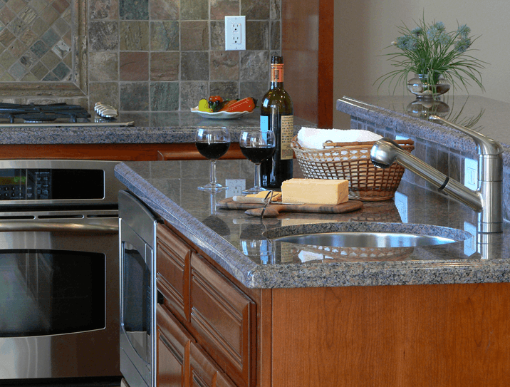 Close up of kitchen island bar with marble counter tops and custom stone backsplash