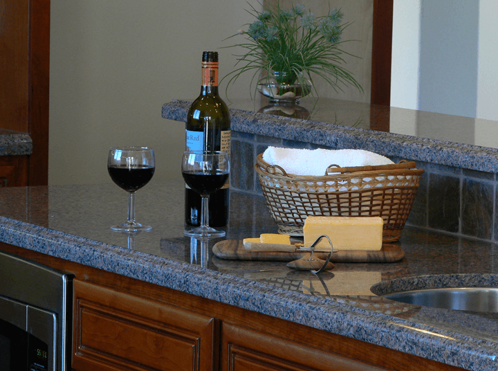 Close up of kitchen island bar with marble counter tops and custom stone backsplash