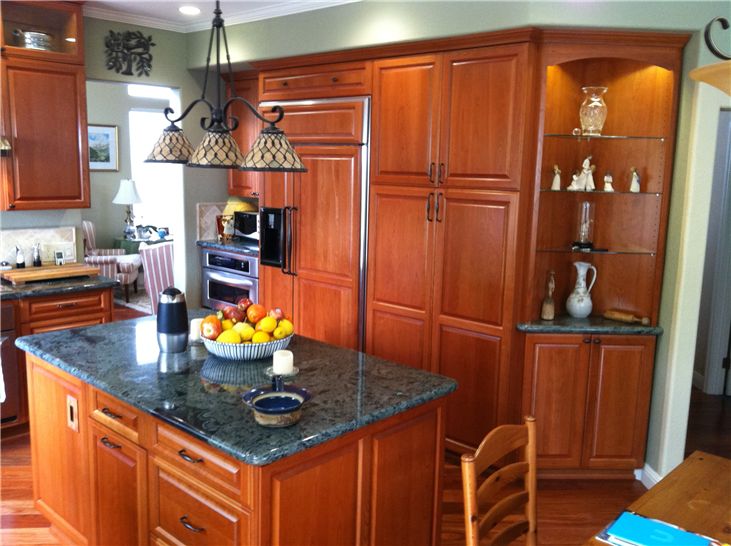 Interior kitchen with stained wood custom cabinets and wood panel refrigerator accent