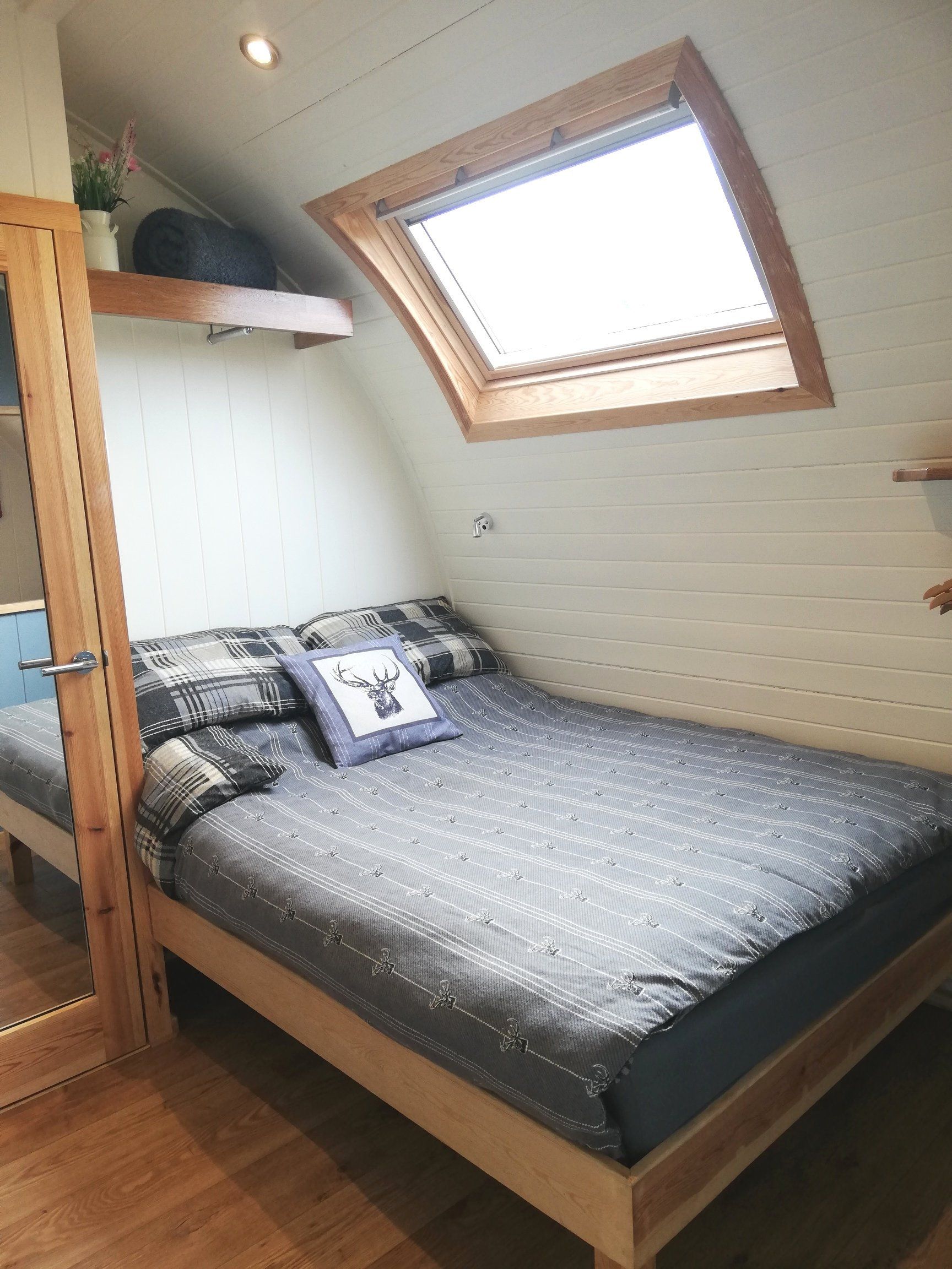 A bedroom with a bed and a window on the ceiling