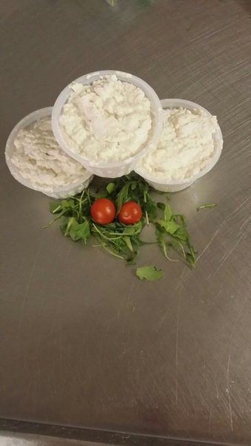 una ciotola di legno con della ricotta e una foglia di basilico