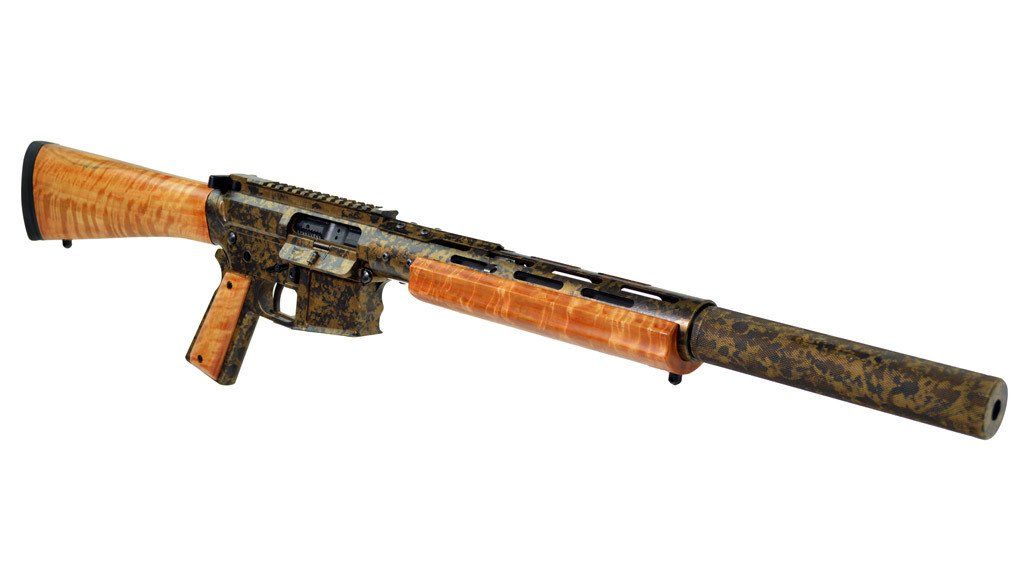 Wood-grained rifle with camouflage body and a large silencer, lying horizontally against a white background.