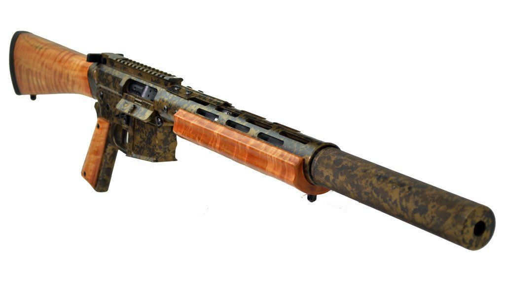 Assault rifle with wooden stock, foregrip, and suppressor. Camo-patterned metal finish.