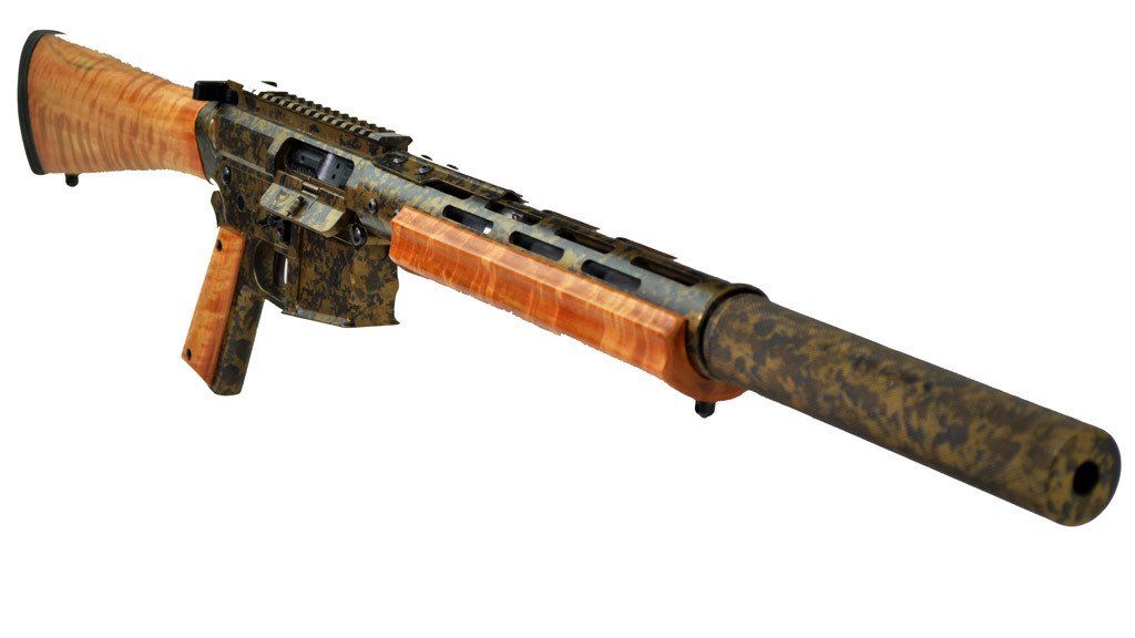 Tan and camouflage patterned rifle with wooden stock and handguard, with a suppressor.