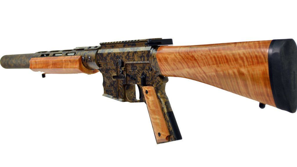 Custom rifle with brown wood stock and handguard, ornate patterned receiver, and black muzzle.