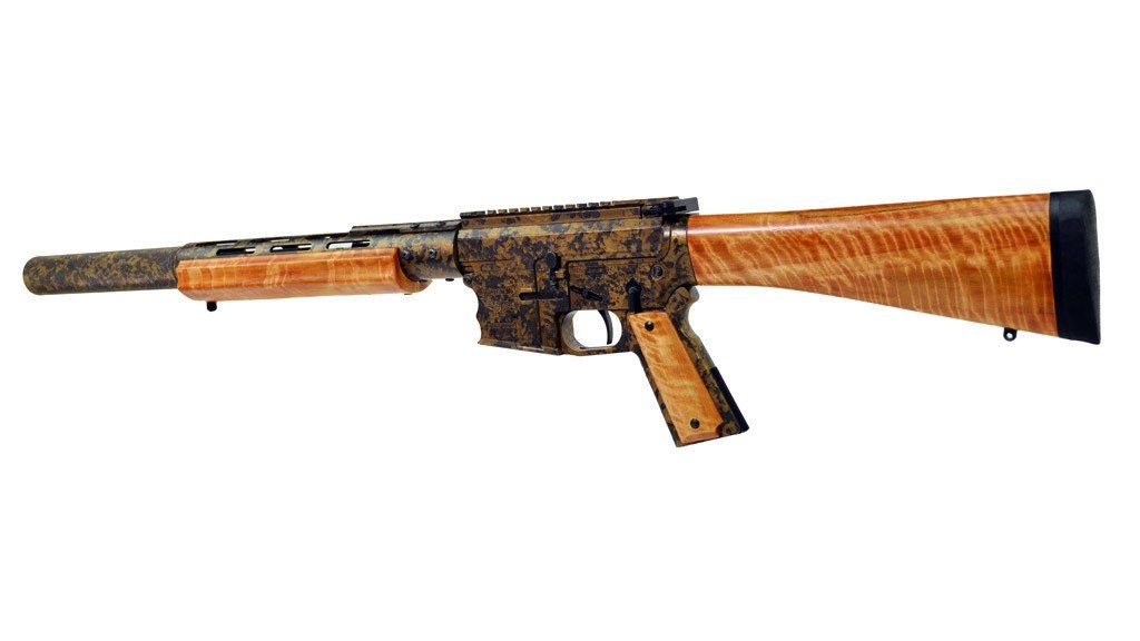 Rifle with wood grain stock and handguard, with ornate dark patterned finish on the receiver and barrel.