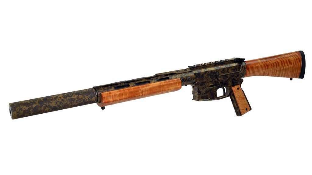 Tan and black rifle with long suppressor, wood grain stock, and forearm.