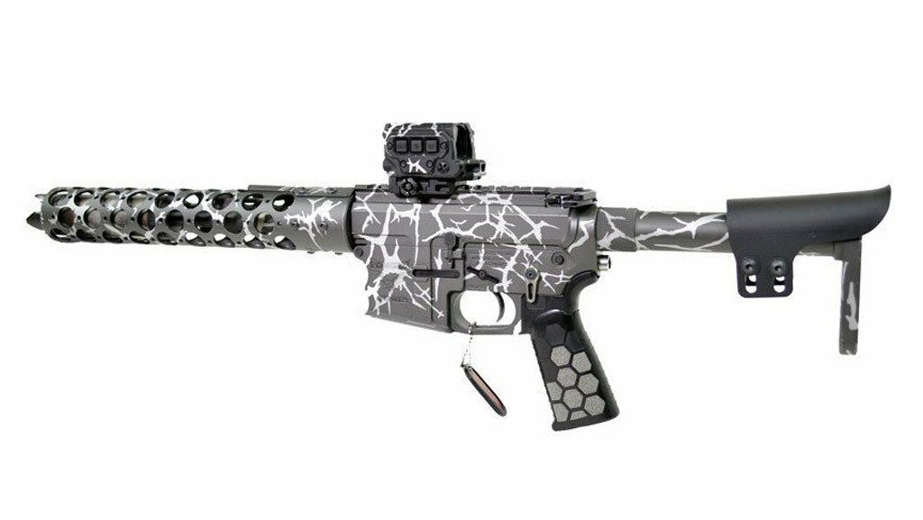 Gray and white camouflage AR-15 style rifle with a red dot sight and honeycomb grip.