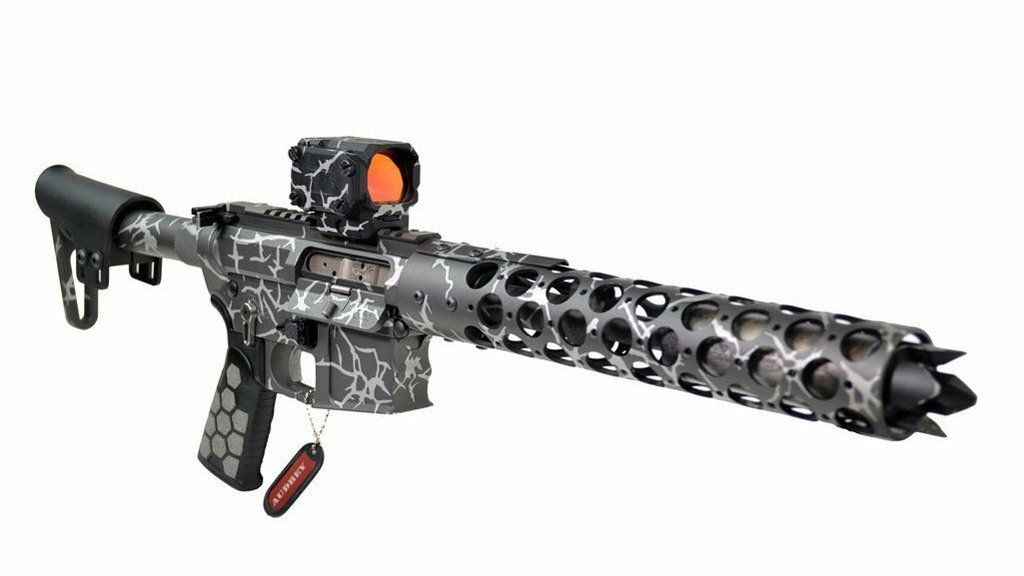 Customized rifle with red dot sight, gray and black camouflage pattern, perforated barrel, and muzzle device.
