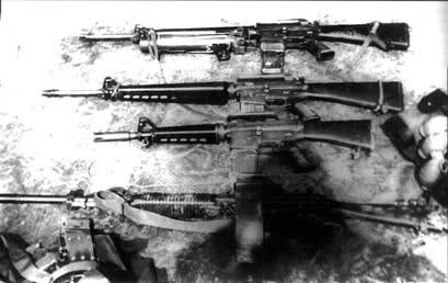 Four rifles lying side-by-side on a surface. Black and white photo.