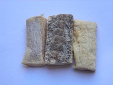 Three rectangular, dried fish treats on a white background. The center one is darker, with textured skin.