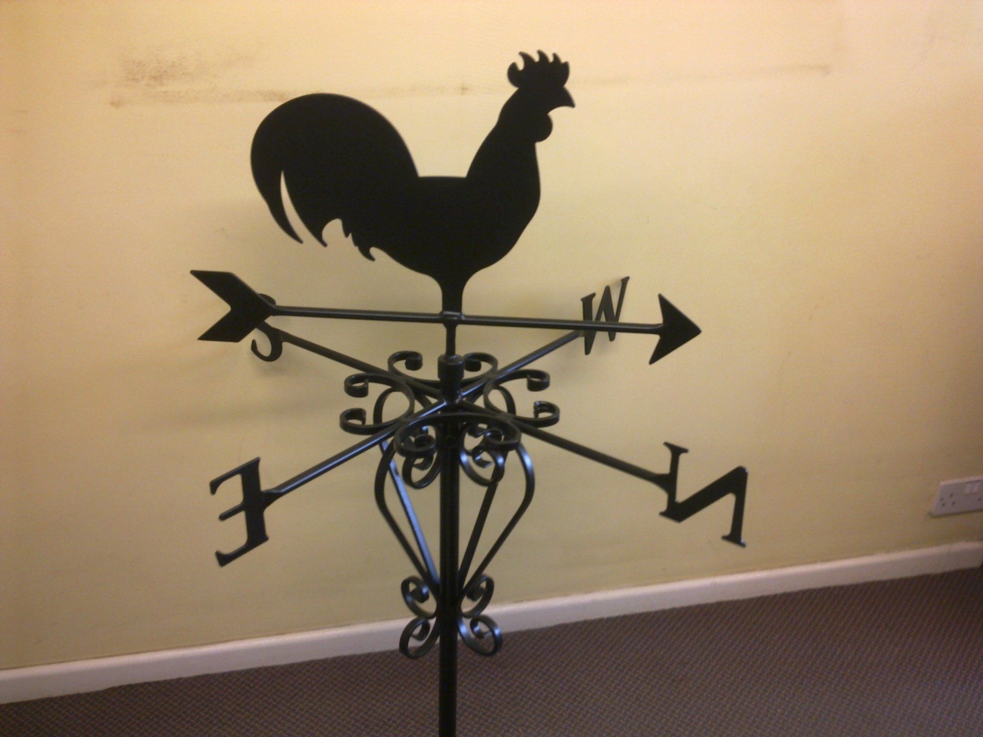 Black rooster weather vane with directional arrows.