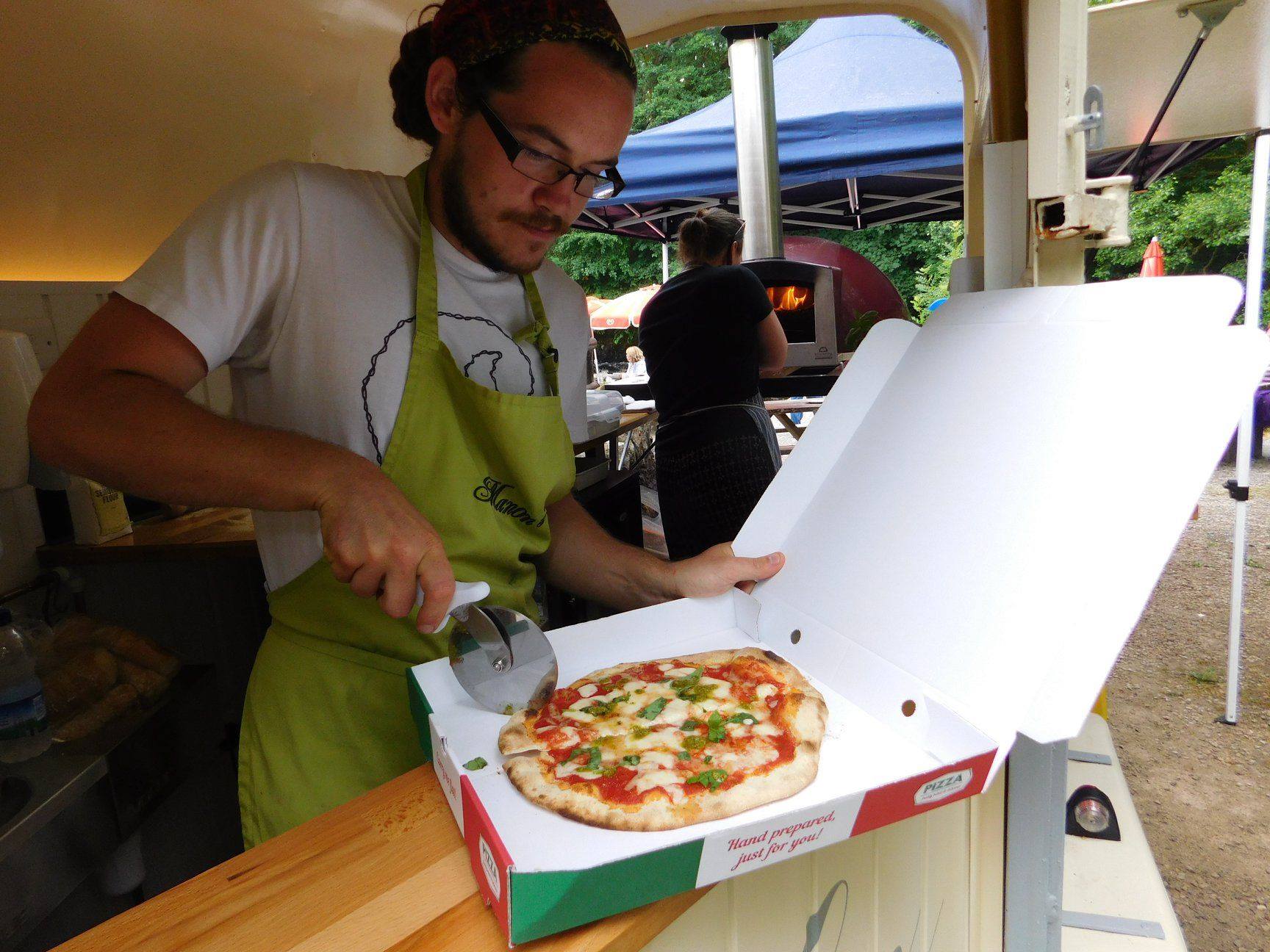 A freshly baked pizza being sliced for a customer