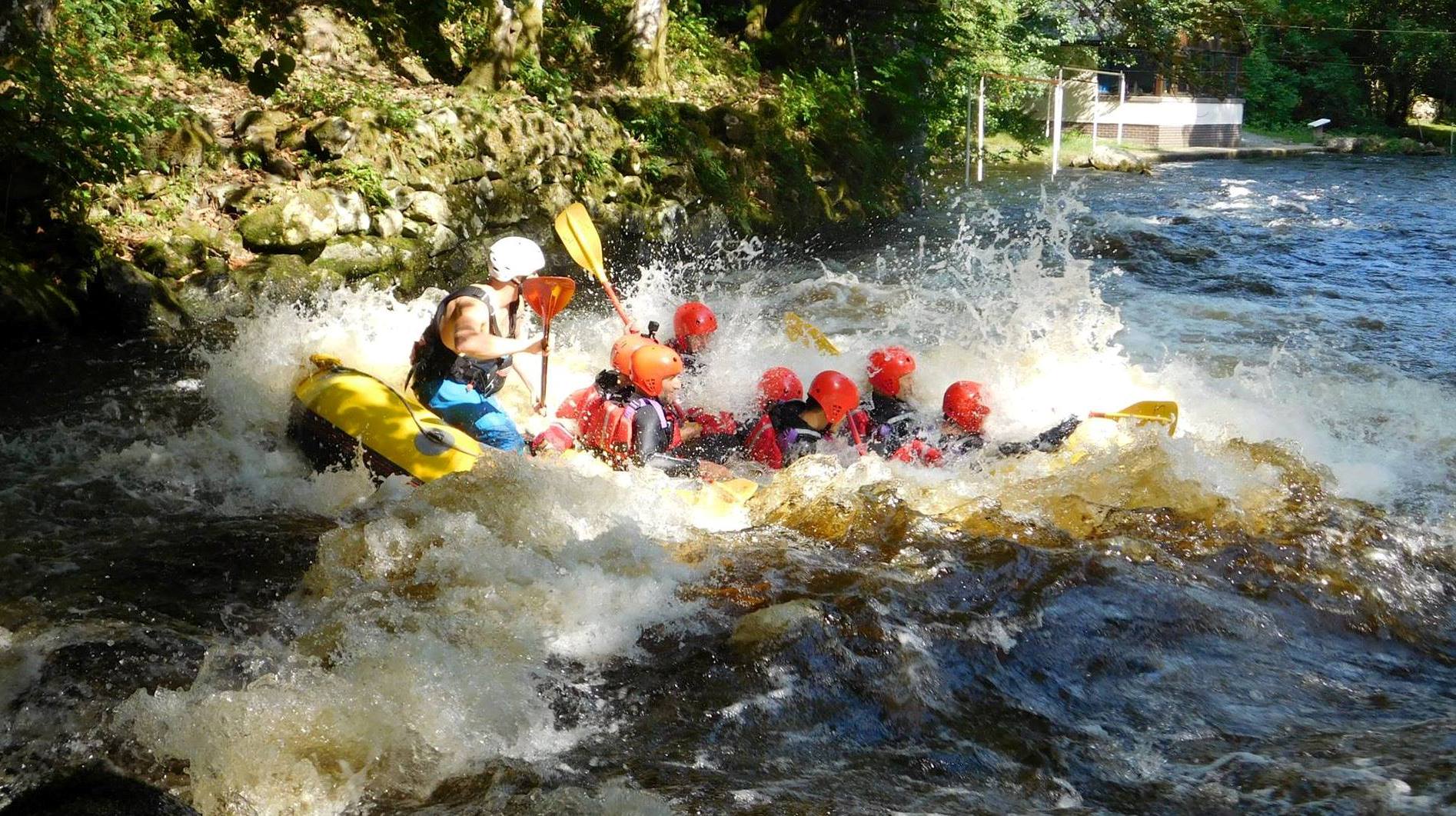 A raft crashing into a rapid with water spraying everywehre