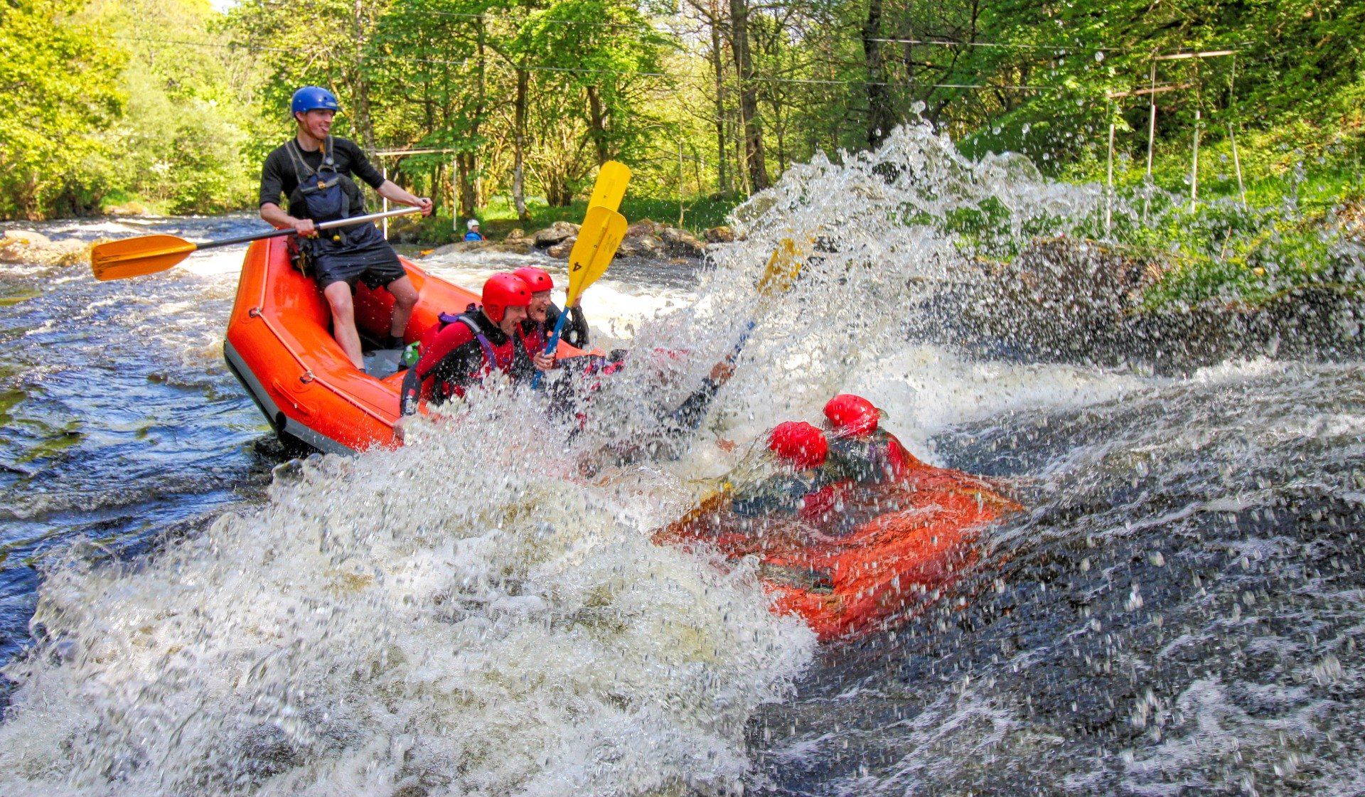 A raft dunking into a rapid so that the people in the front of the raft are underwater