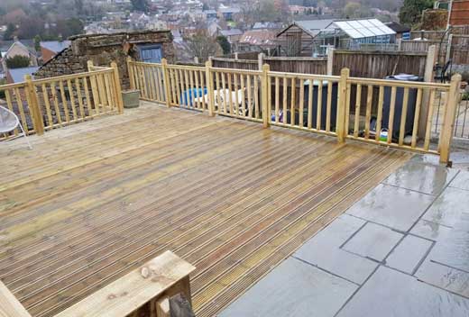 Light coloured raised wooden decking with a similar wooden fence around it