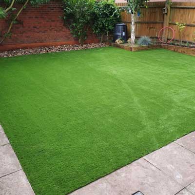 A square lawn surrounded by gravel, pathways, and wooden fencing