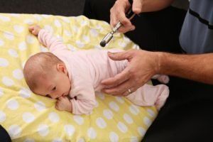 A baby is being examined by a chiropractor on a table.