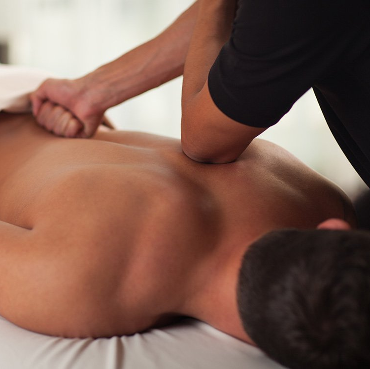 A man is laying on a bed getting a massage
