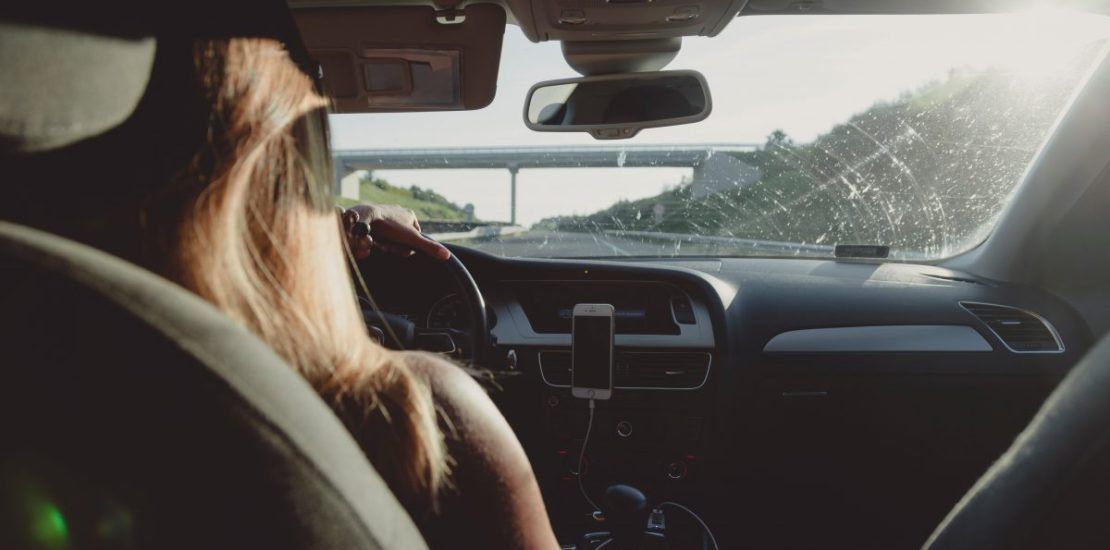 A woman is driving a car on a highway.