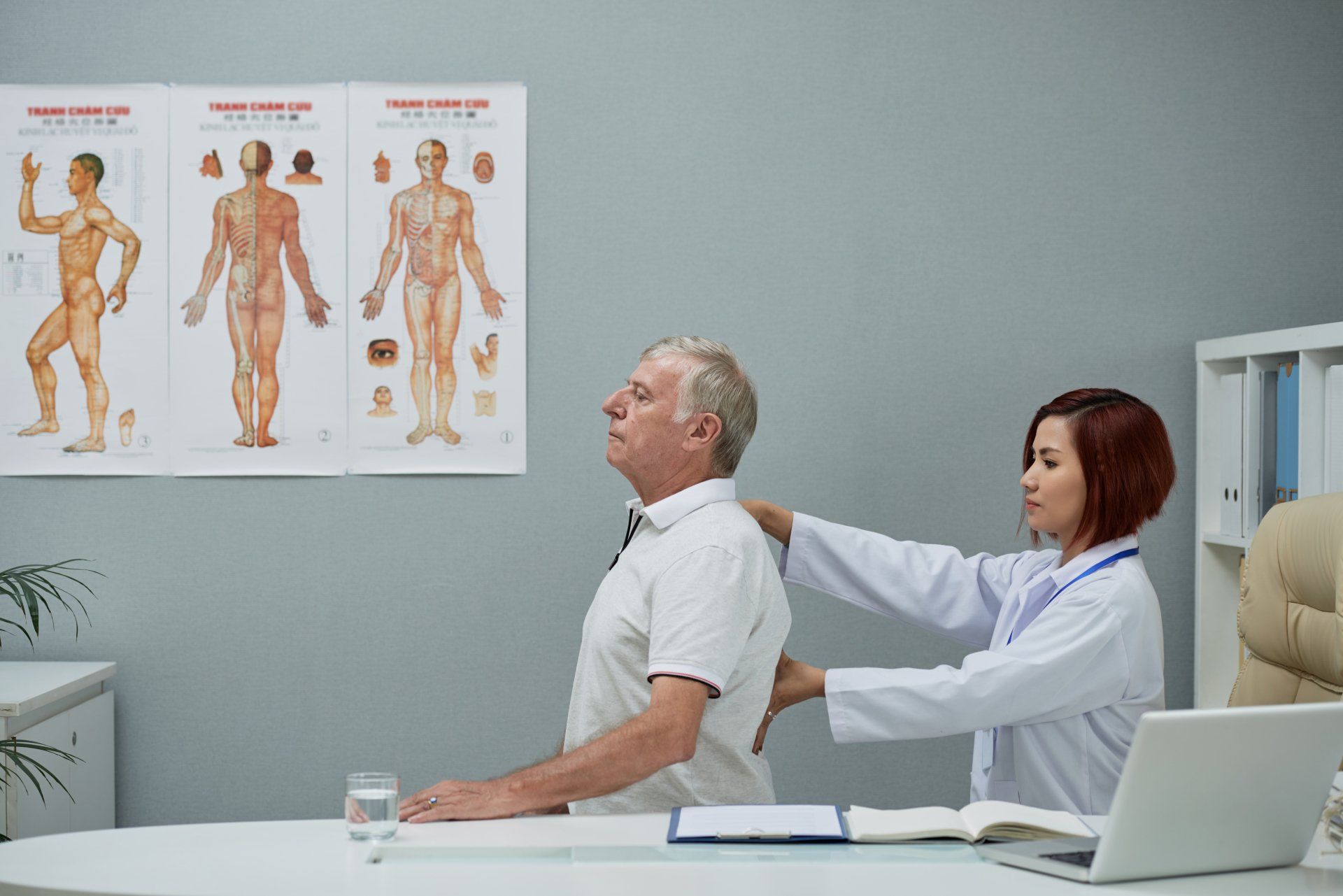 A doctor is examining a man 's back in a hospital.
