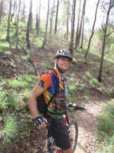 A man is riding a bike on a trail in the woods.