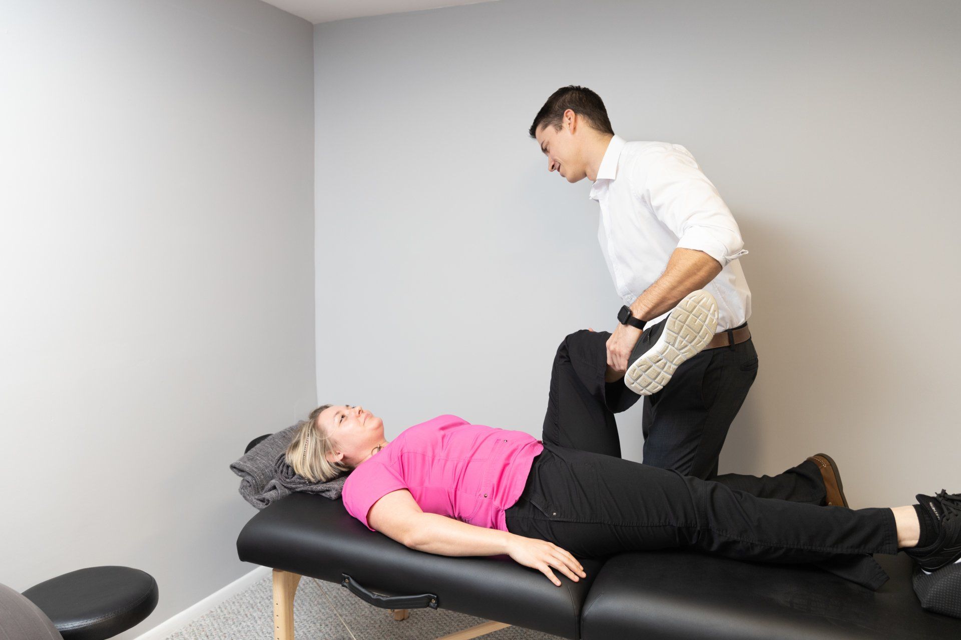 A man is stretching a woman 's leg on a table.
