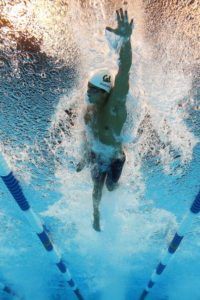 A man is swimming underwater in a pool.
