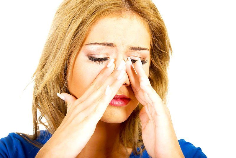A woman is holding her nose because she has a headache.
