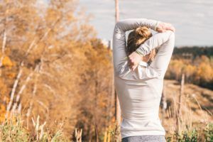A woman is stretching her arms in a field.