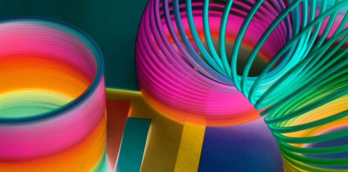 A close up of a rainbow colored slinky toy on a table.