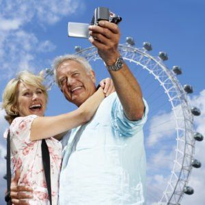 A man and woman are taking a selfie in front of a ferris wheel